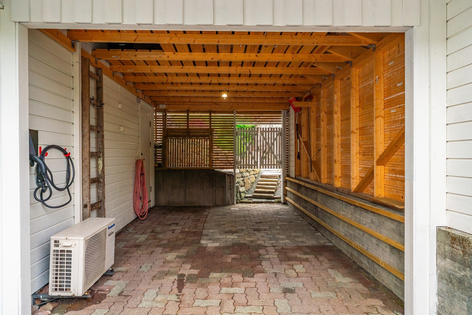 Carport med elbil lader. Fra carport kan man gå tørrskodd inn i boligen. I bakkant har man videre gangareal til terrasse på oppsiden Galleribilde
