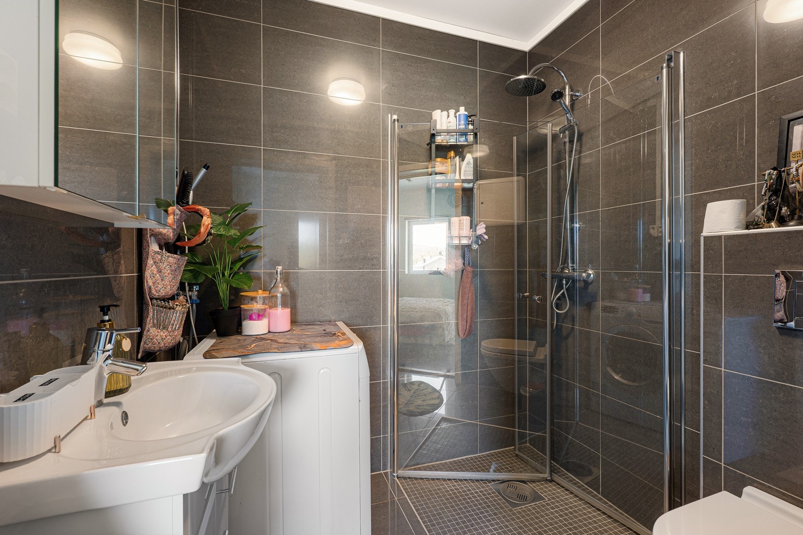 Badet er helfliset og har hvitt servantmøblement, speilskap, veggmontert toalett, dusjhjørne med regnfallsdusj og hånddusj - samt opplegg for vaskemaskin. I gulvet er det lun, behagelig varme. Galleribilde