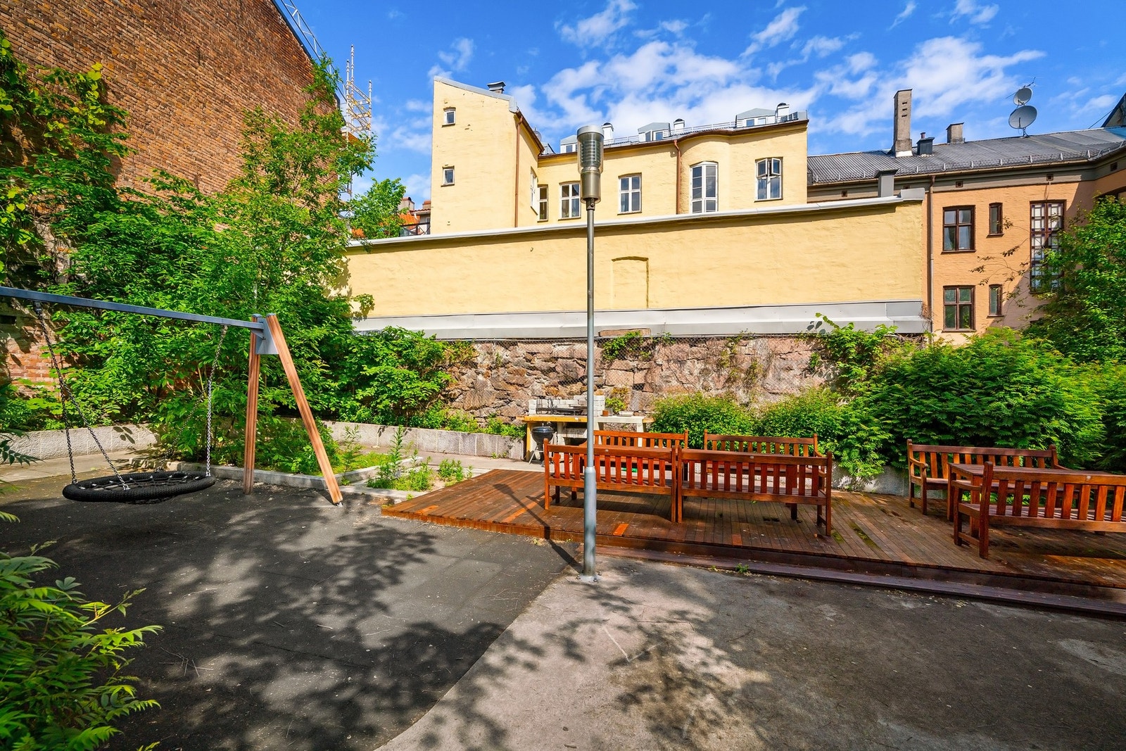 Det er brosteinsbelagte arealer og terrasser med flere sittegrupper og benker til felles glede, samt huskestativ for de yngste. Galleribilde