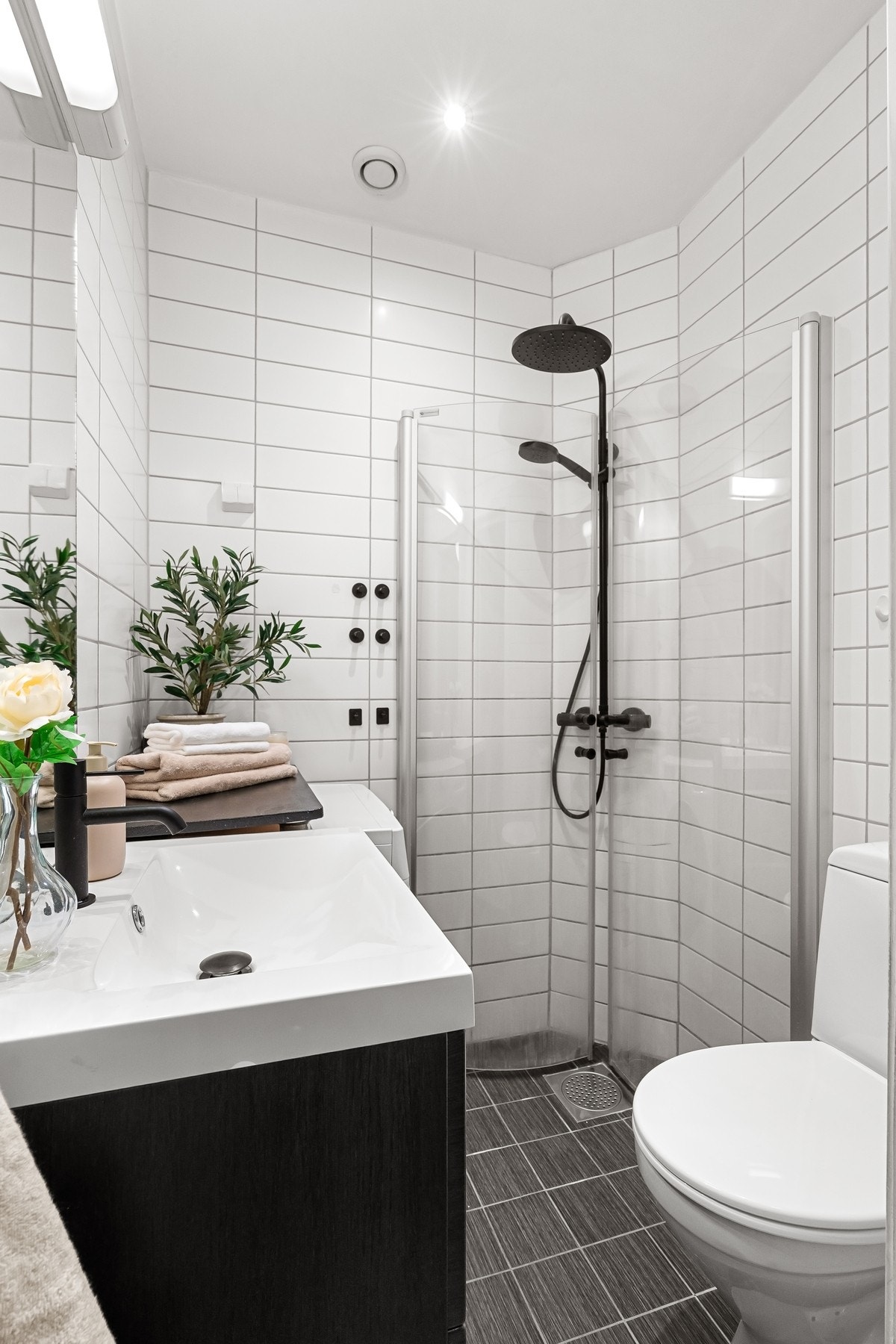 Badet har speil med overlys, toalett, og dusjhjørne utstyrt med innfellbare glassdører, samt regnfallsdusj og hånddusj i trendy, sort utførelse. Galleribilde