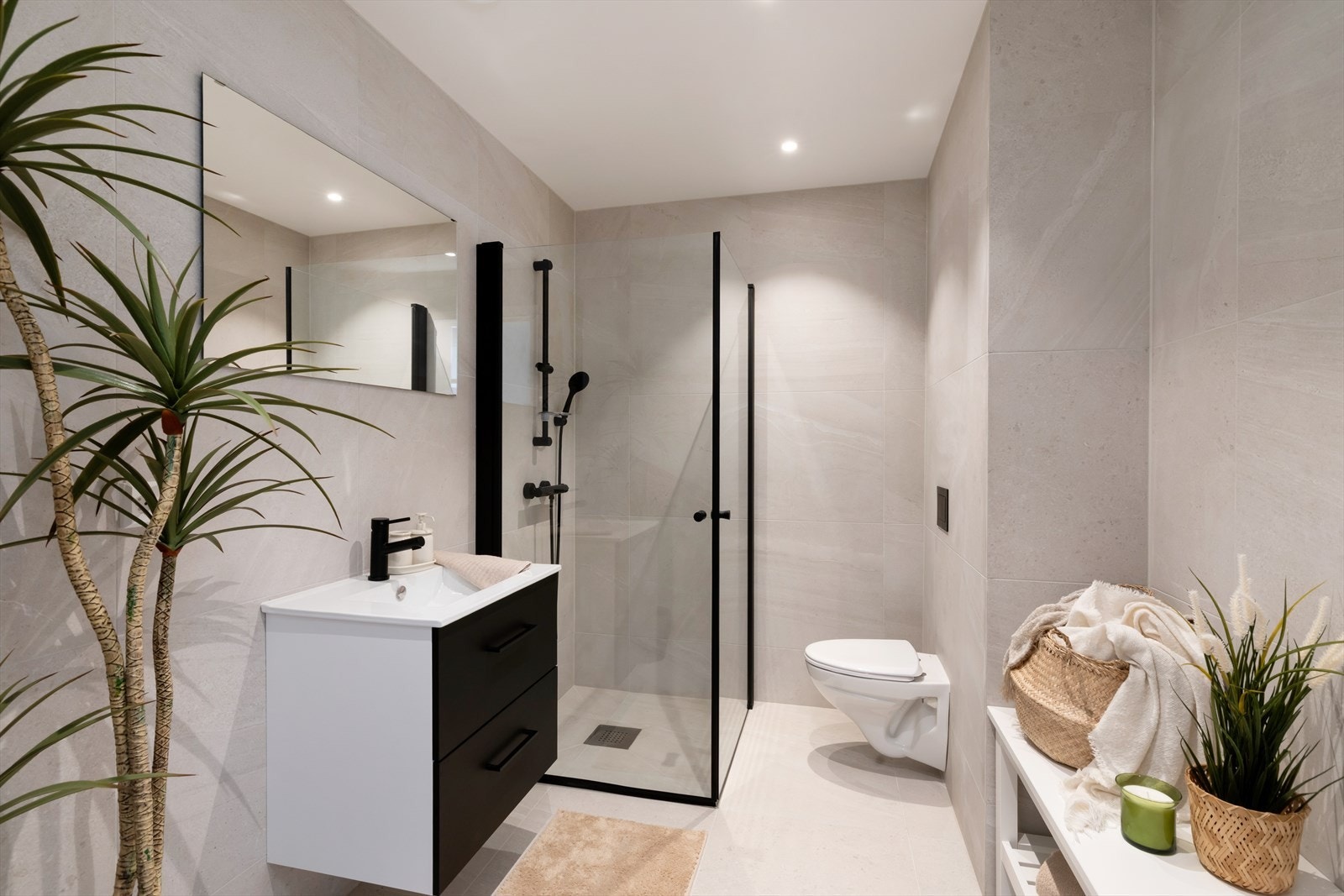 Badet er delikat flislagt og utstyrt med vegghengt toalett, servant, dusjhjørne og downlights i himlingen. Det er opplegg for vaskemaskin og tørketrommel. Galleribilde