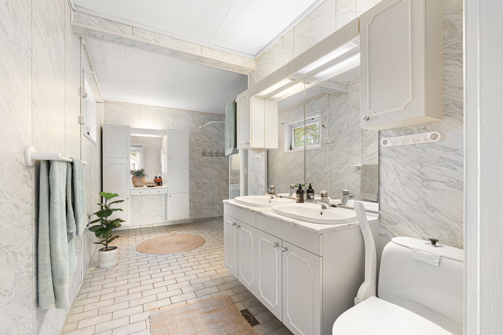 Badet har en romslig utforming med dobbel servant og godt med skapplass. Galleribilde