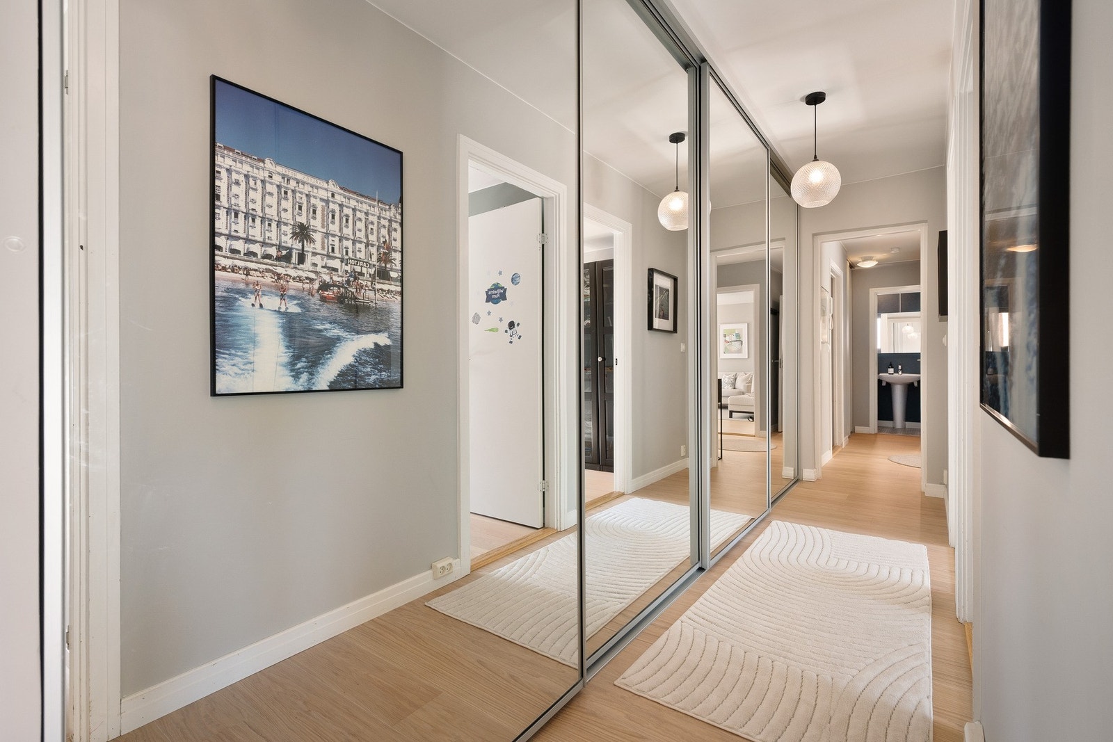 Stor skyvedørsgarderobe i gangen med speilfronter. I den innerste delen av garderoben er det opplegg for vaskemaskin. Galleribilde