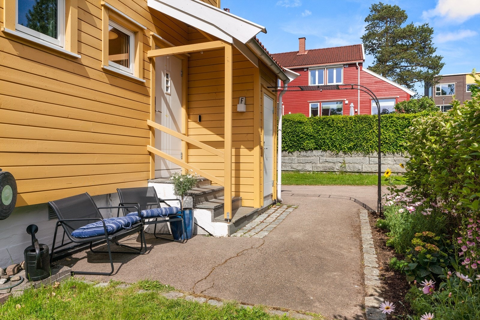 Overbygget inngangsparti med ny, fabrikksmalt ytterdør fra 2020 og tilknyttet privat bod. Galleribilde