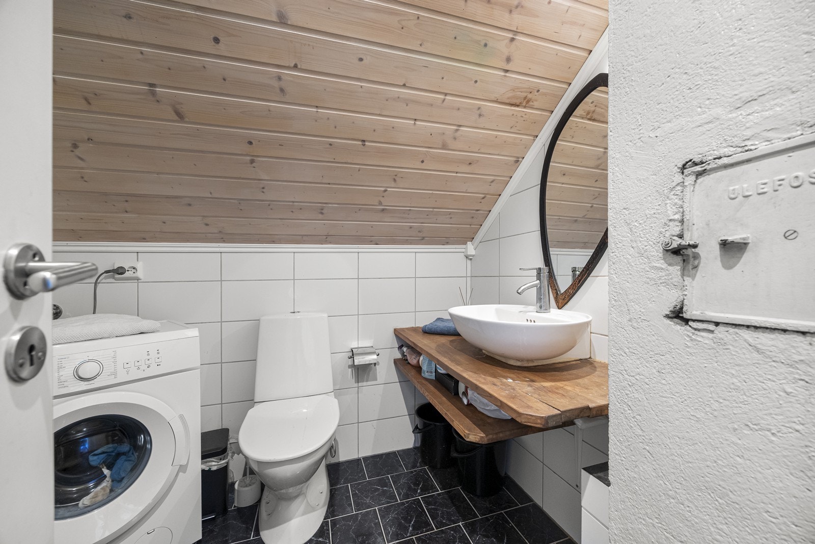 Baderommet har flislagte gulv og vegger, samt dusj bak døren og opplegg til vaskemaskin. Galleribilde