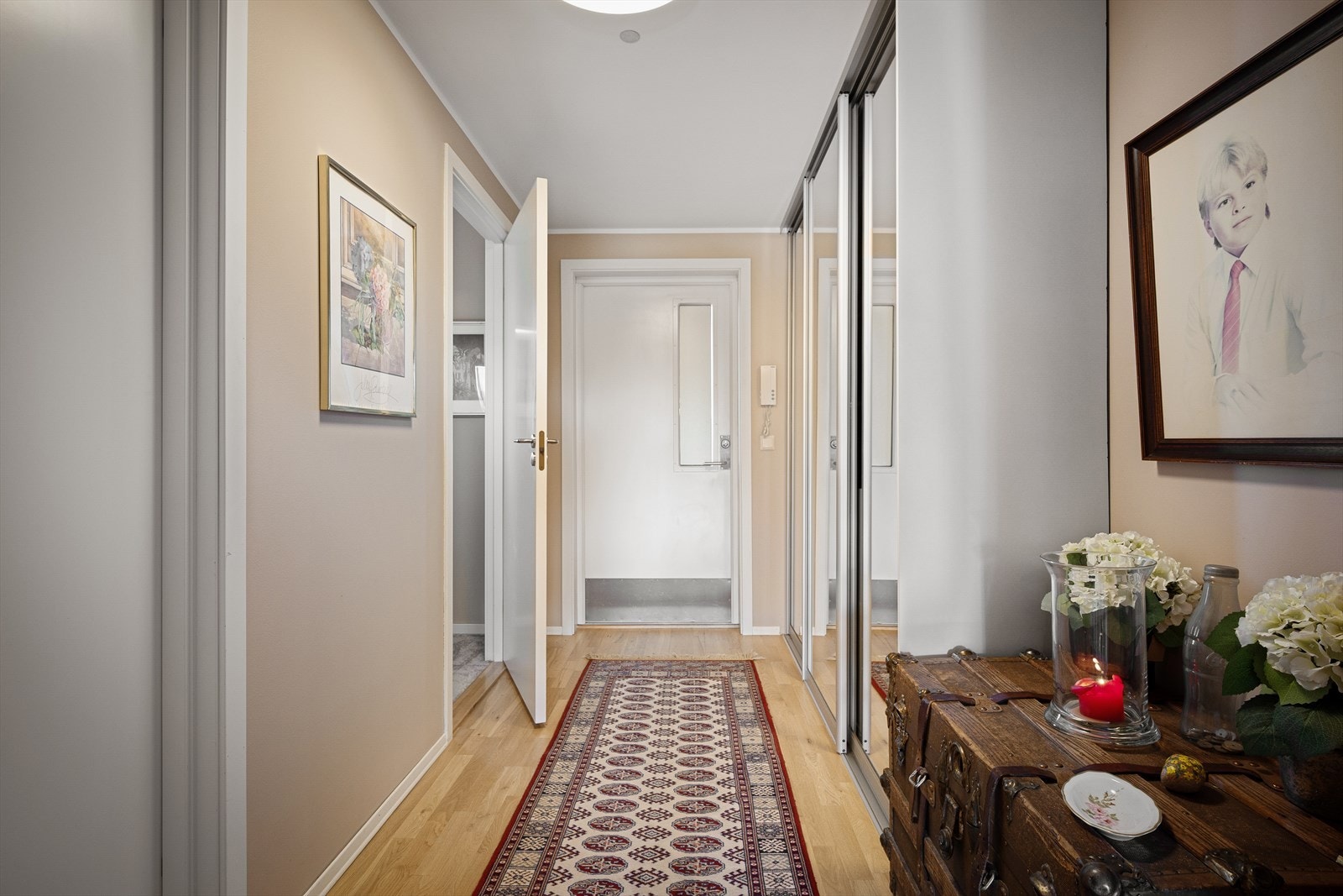Entreen har lyse overflater, parkettgulv og skyvedørsgarderobe med speilfronter. Galleribilde