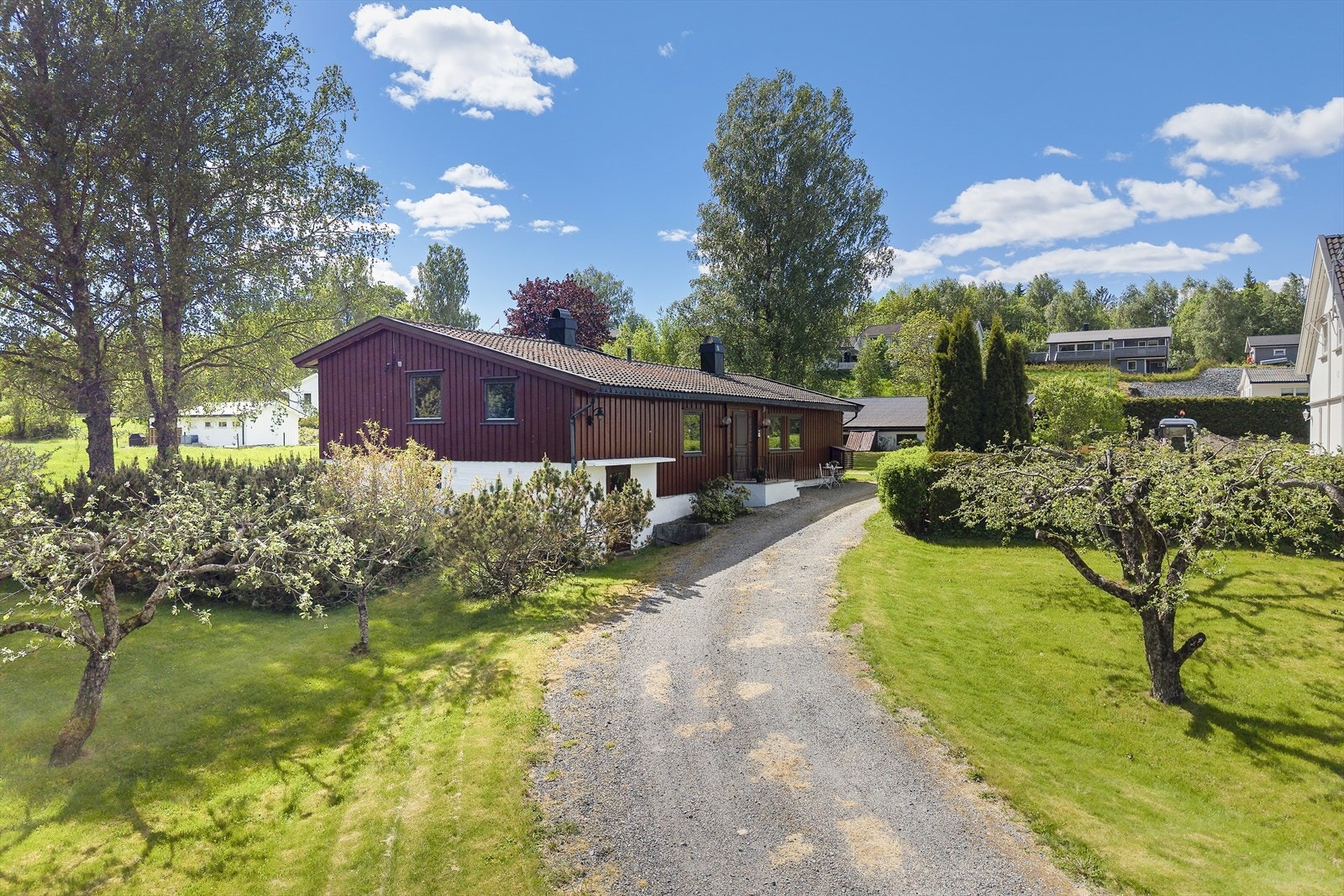 Tomten er pent opparbeidet med plen, gruset adkomst og diverse beplantning. Galleribilde