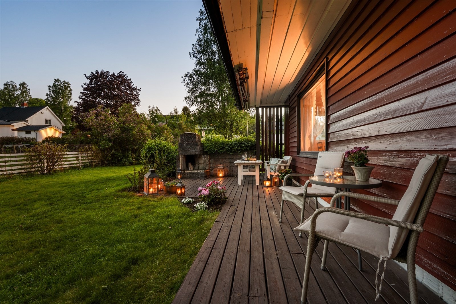 Fra stuen er det utgang til en terrasseplatting med utepeis, omkranset av en stor, grønn hage. Galleribilde