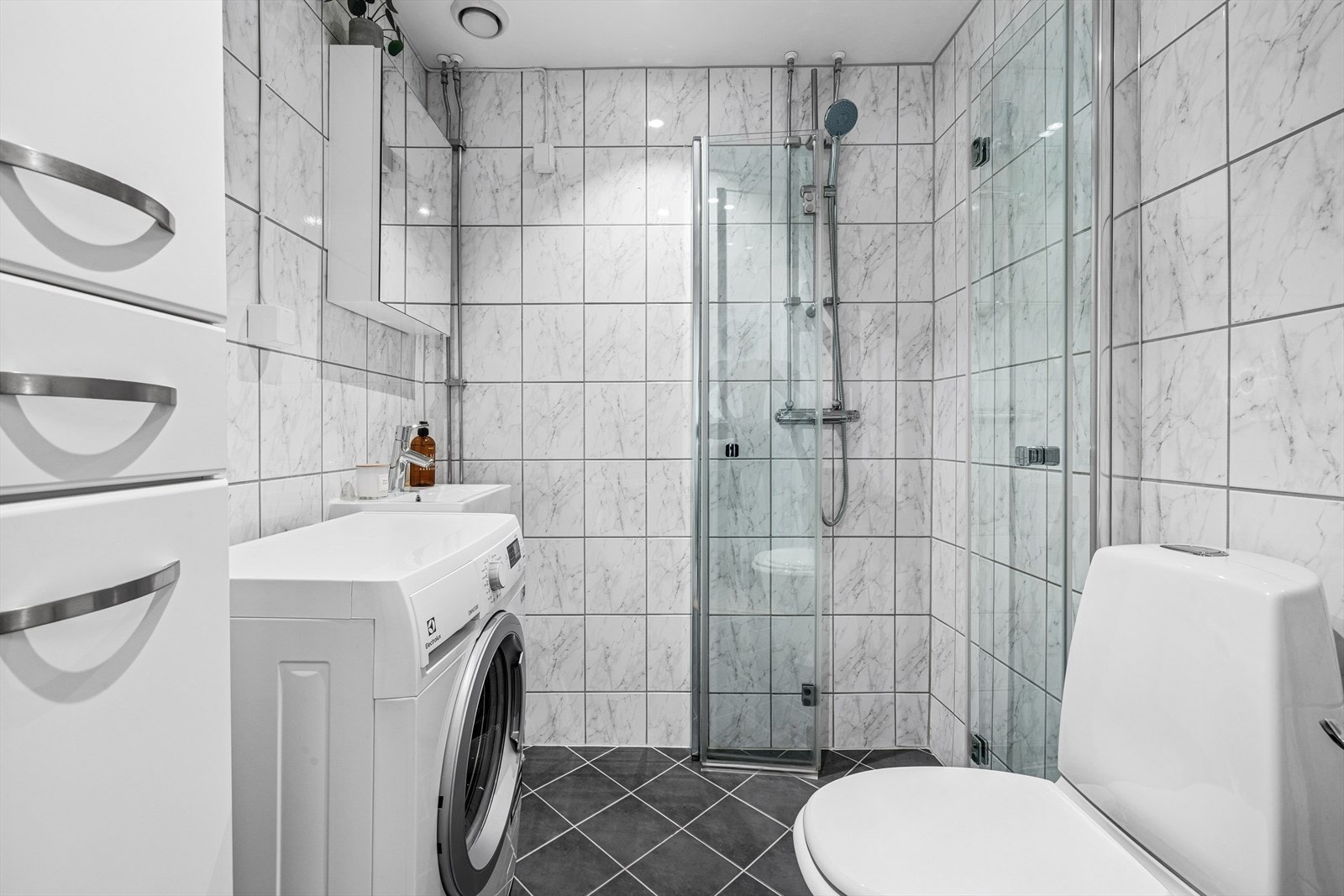 Flislagt bad med dusjhjørne med innfellbare glassdører. Badet ble renovert i regi av aksjelaget i 2009. Galleribilde