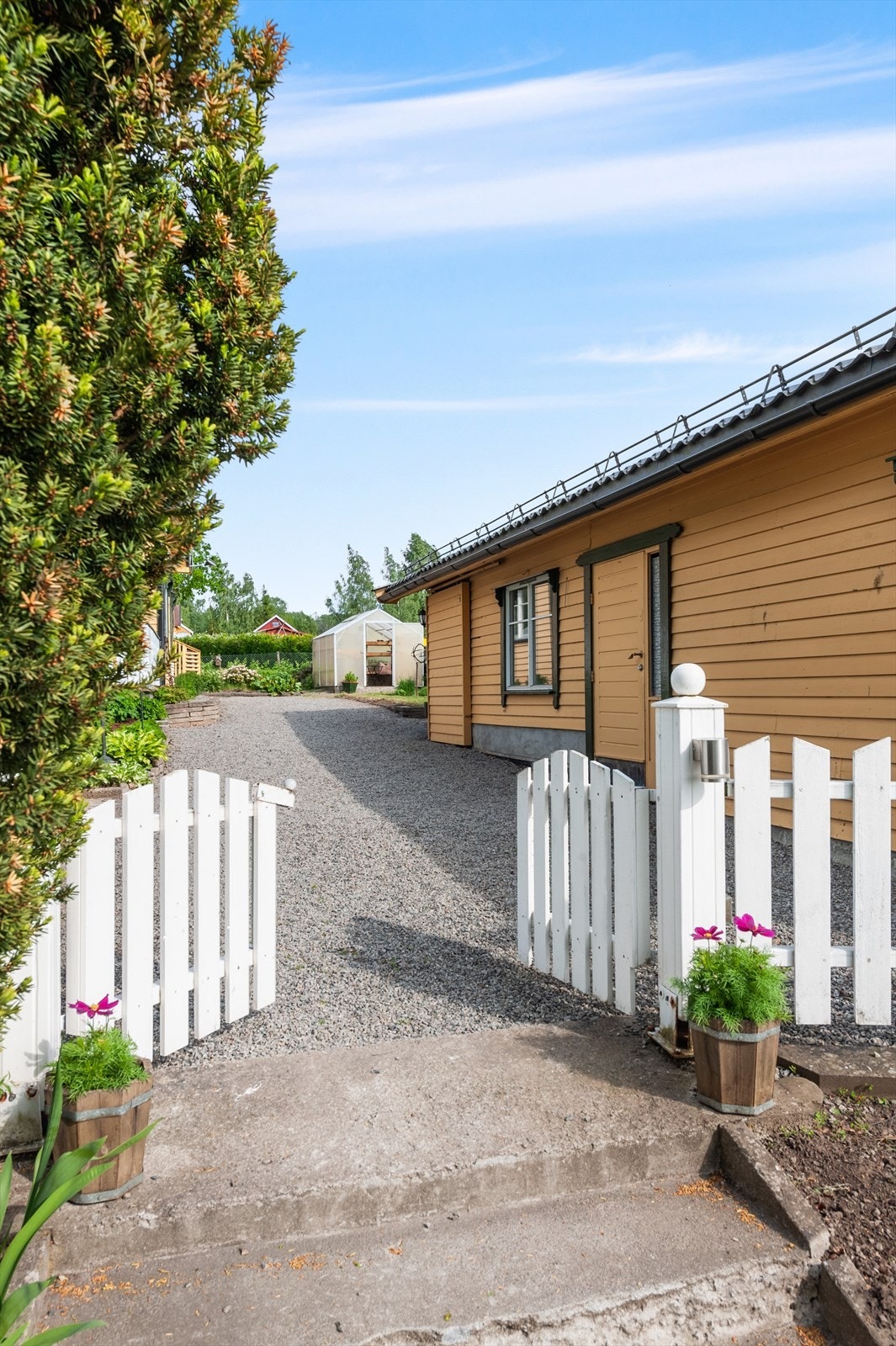 Tomten er pent opparbeidet med plen, beplantning og en sjarmerende hageport. Galleribilde