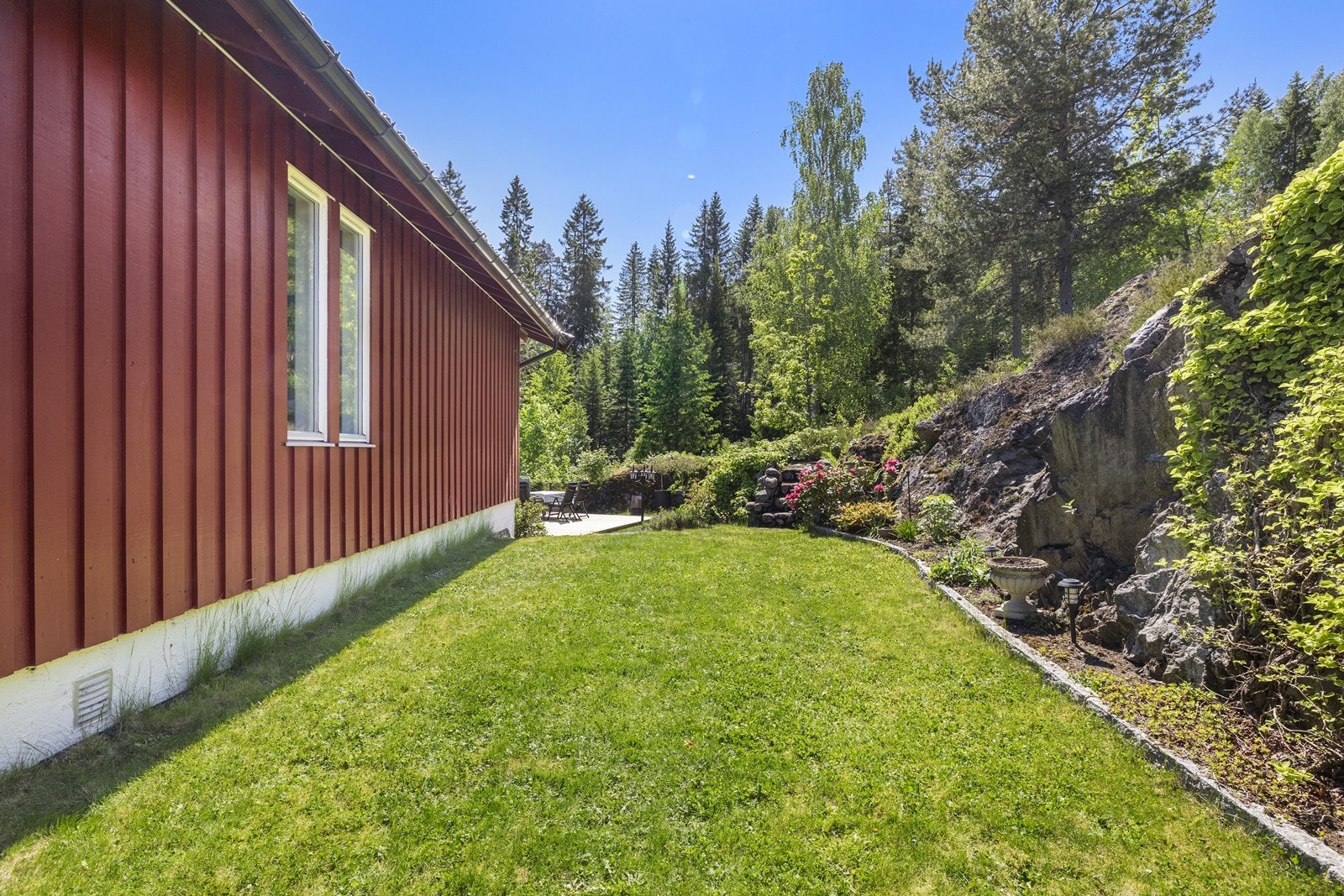 Et trivelig uteområde med plen, beplantning og plass til å nyte fine dager utendørs. Galleribilde