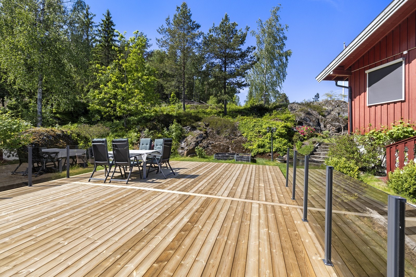 Uteområdet er pent opparbeidet med en kombinasjon av fine hageområder, naturtomt med fjell og diverse beplantning Galleribilde