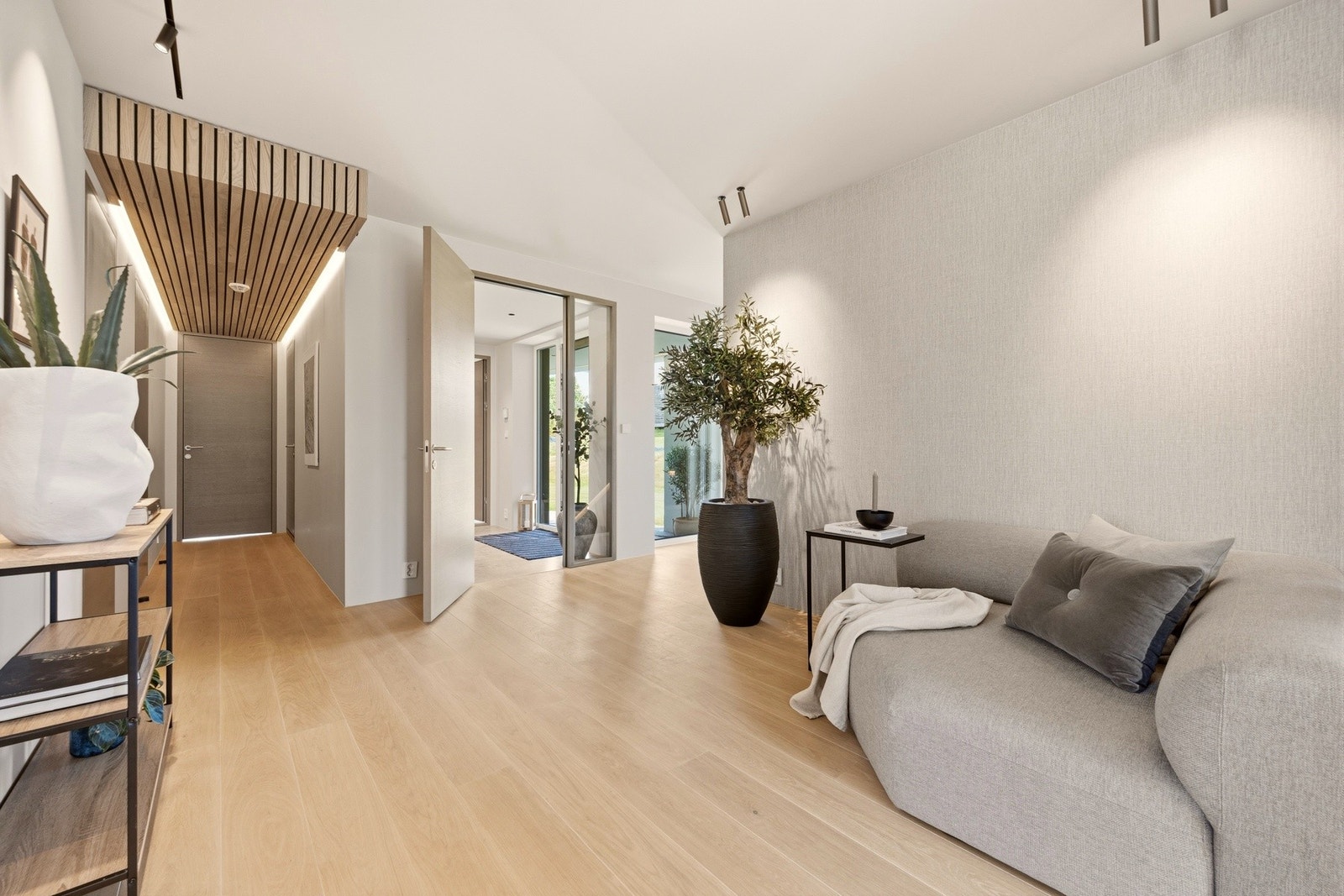 Fra inngangspartiet kommer man inn i et generøst fellesrom med plass til både opphold og sosiale soner. Nedsenket spilehimling i ask med integrert LED-belysning gir rommet karakter og en varm, innbydende atmosfære. Galleribilde