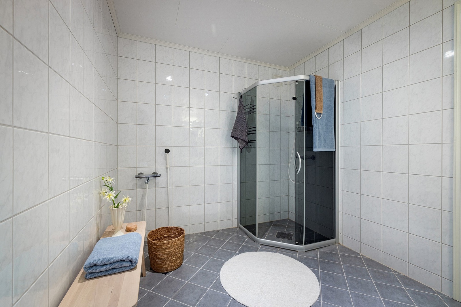 Delikat, helfliset bad med varmekabler i gulvet. Badet er innredet med dusjsone med mørke glassvegger og frittstående toalett. Galleribilde