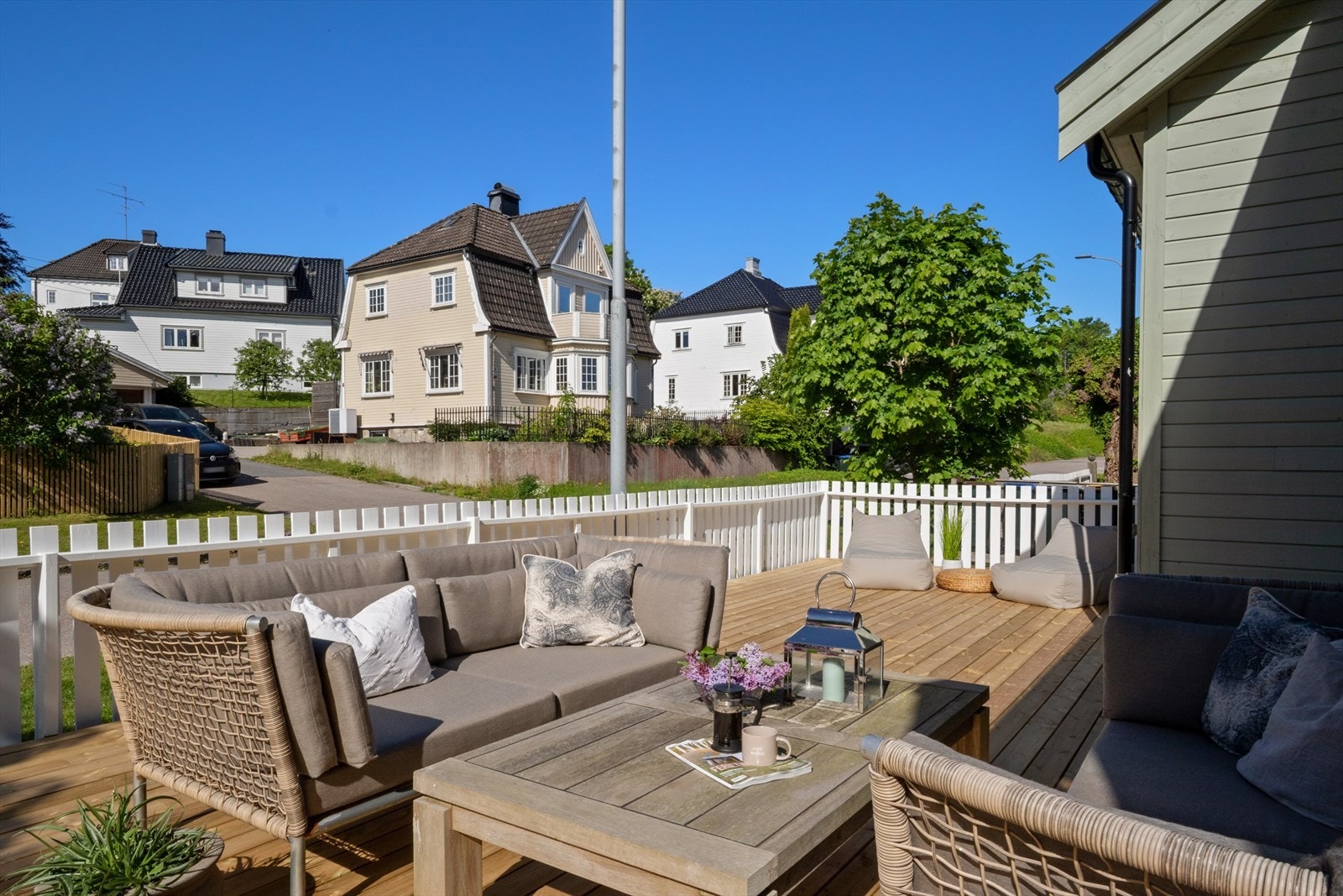 Verandaen er bygget i tre og har et hvitt rekkverk som rammer inn uteplassen. Galleribilde