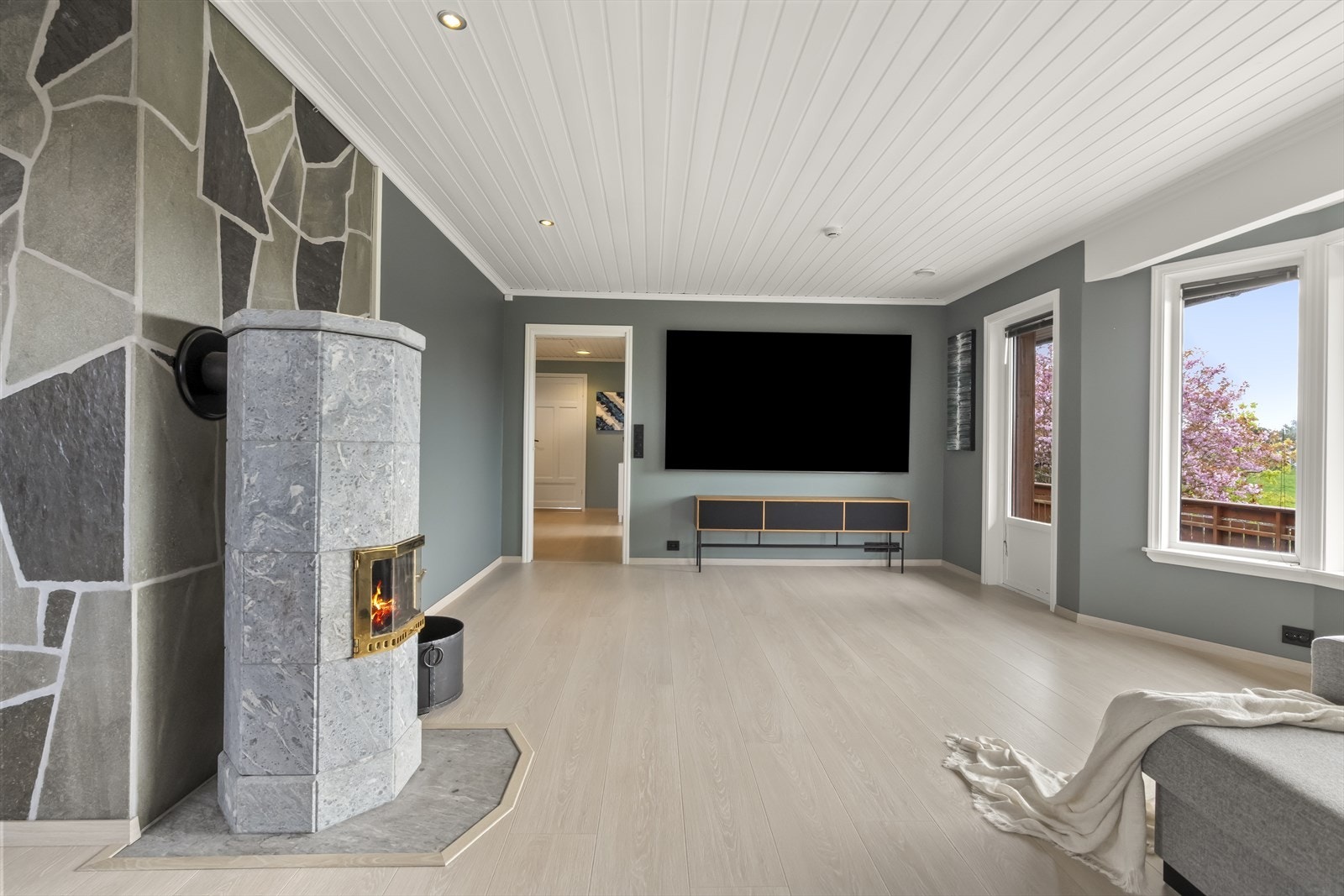 Lys og romsleg stove med moderne peis og store vindauge som gir flott utsikt. Perfekt for avslapning og hygge. Galleribilde