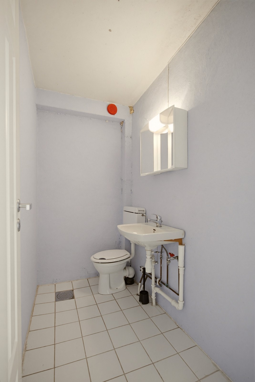 WC med flislagt gulv, toalett og servant. Galleribilde