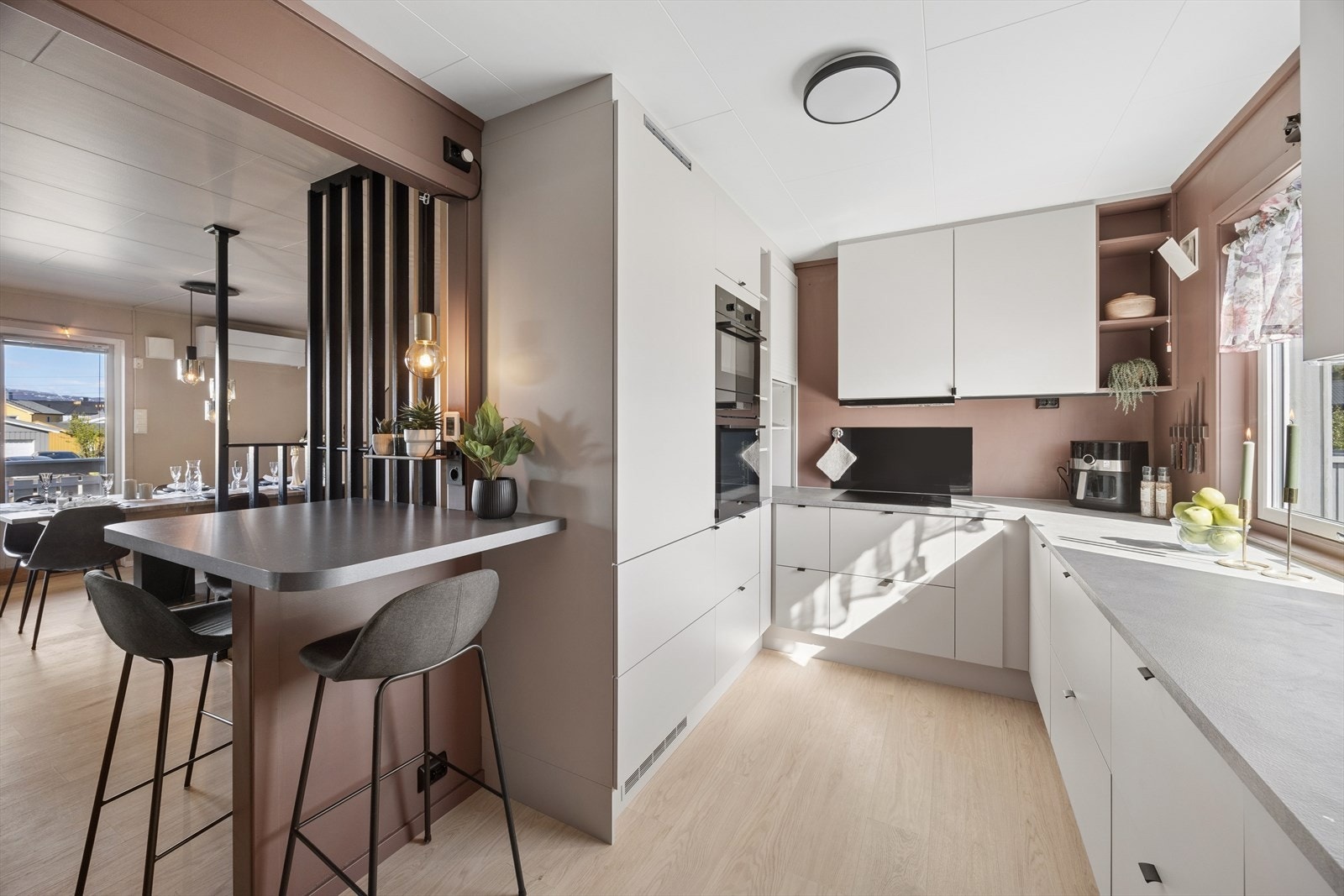 Kjøkkenet har en moderne innredning med hvite glatte fronter, laminat benkeplate og en praktisk barløsning mot stuen. Galleribilde