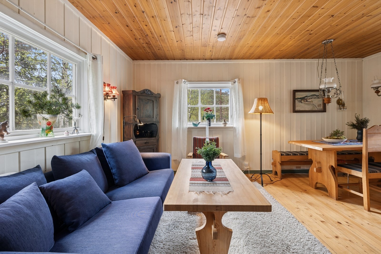Stuen har plass til både sofagruppe og spisebord, med vegger og himling i panel som gir en klassisk hytteatmosfære. Galleribilde