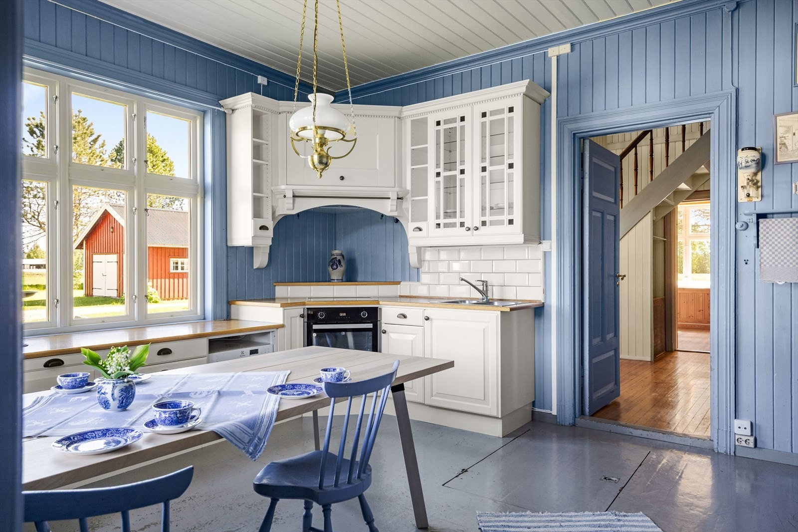 Kjøkkeninnredning i sveitserstil i vinkel med profilerte fronter, laminat benkeplate med heltre front og nedfelt rustfri servant med to kummer. Galleribilde