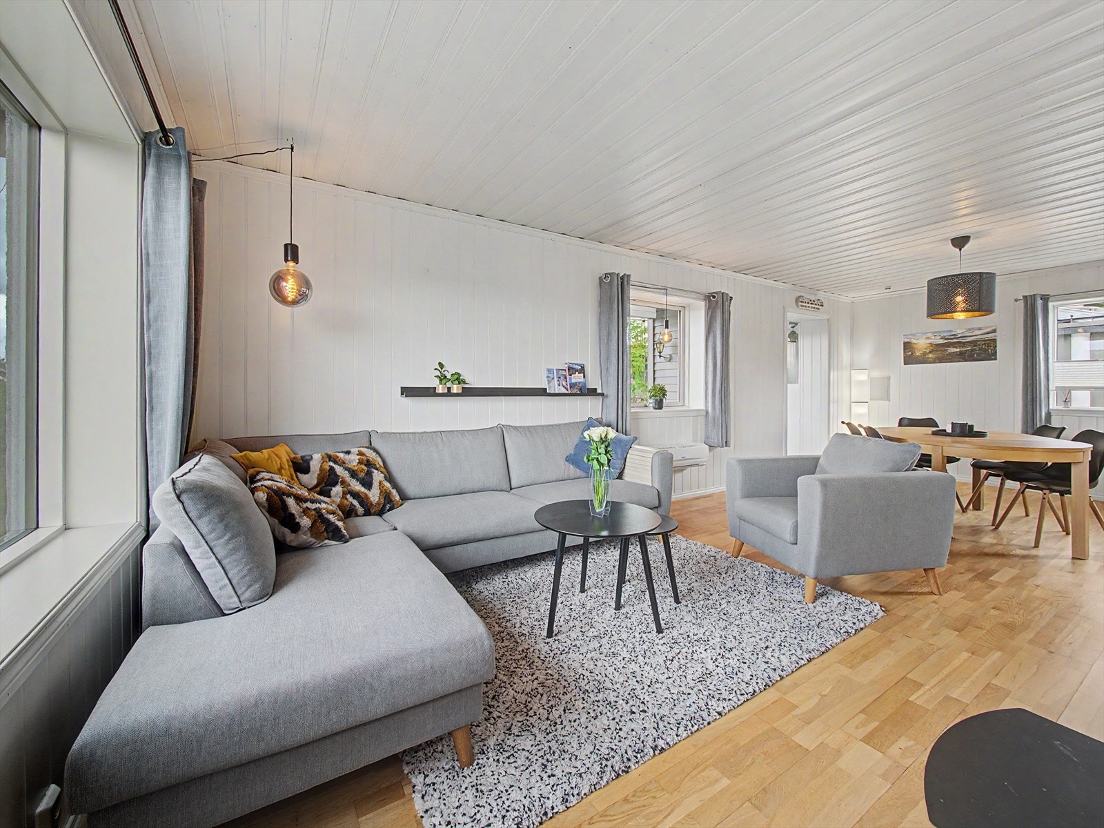Varmepumpe er montert på yttervegg, strategisk plassert midt mellom sofa-sone og spisebord. Galleribilde