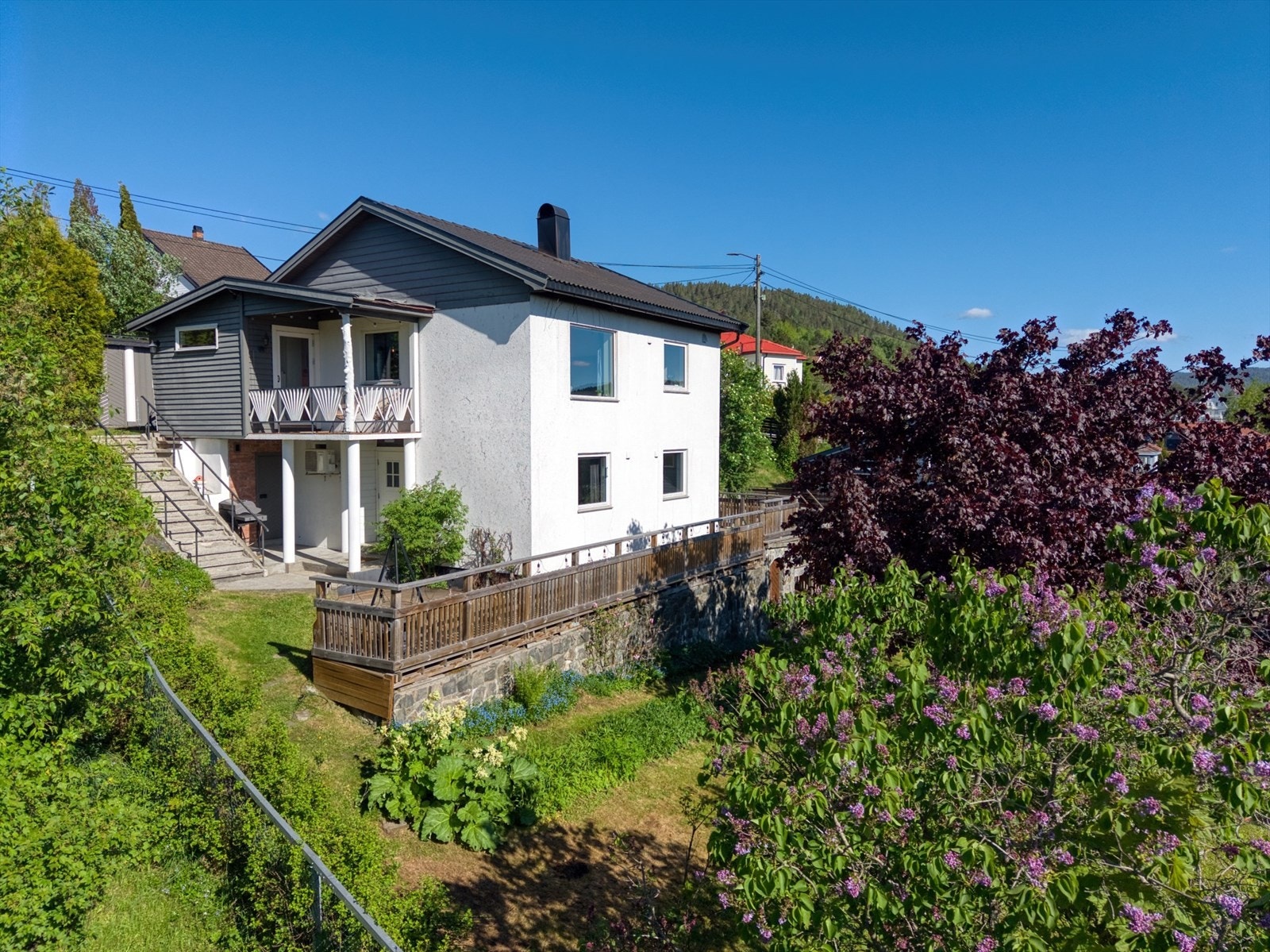Fasade sett fra sør. Eiendommen har ulike terrasser og uteplasser, slik at man enkelt kan tilpasse sol og skygge etter ønske. I etasjen under underetasjen, er det også egen kjeller med adkomst fra hage. Galleribilde