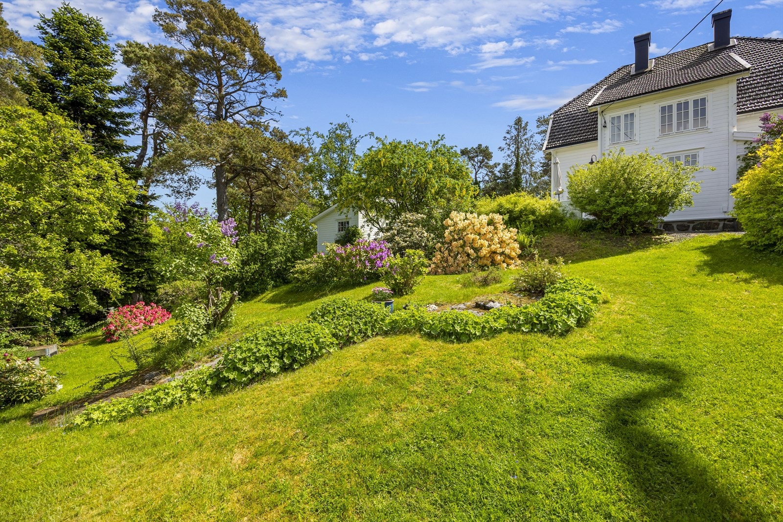 Det er flaggstang i hagen, hyggelig terrasse med drivhus samt stor terrasse oppe ved boligen med sol fra tidlig til sent. Galleribilde