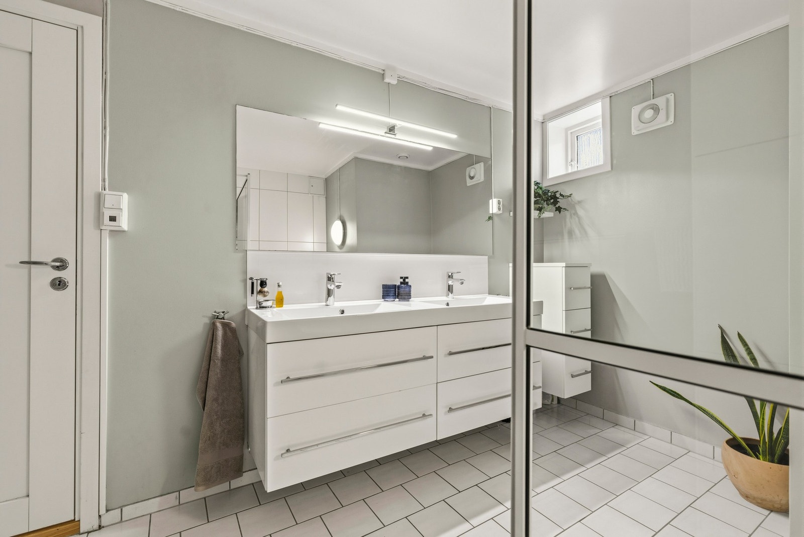 Badet har toalett, dusjvegg i herdet glass, baderoms-innredning med høyglans fronter og 2 heldekkende servanter. Galleribilde