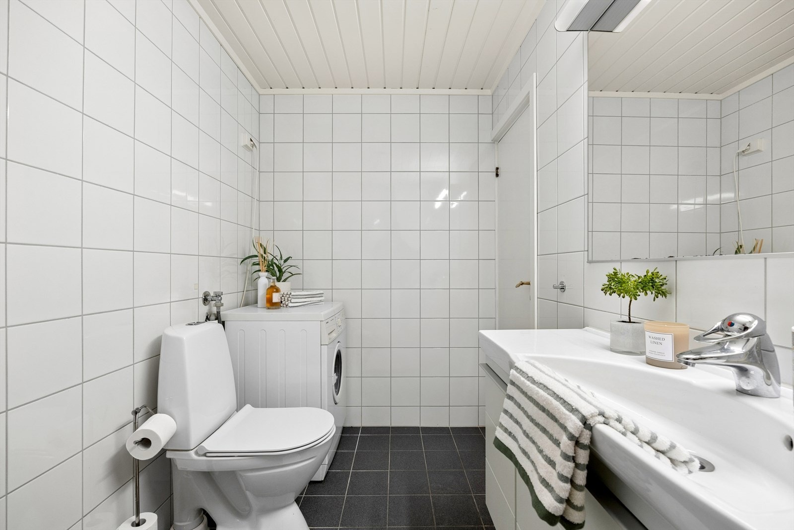 Badet har også plass til vaskemaskin - en praktisk løsning som frigjør plass i resten av leiligheten. Alt av WC, servant og dusjhjørne er samlet på et effektivt areal. Galleribilde