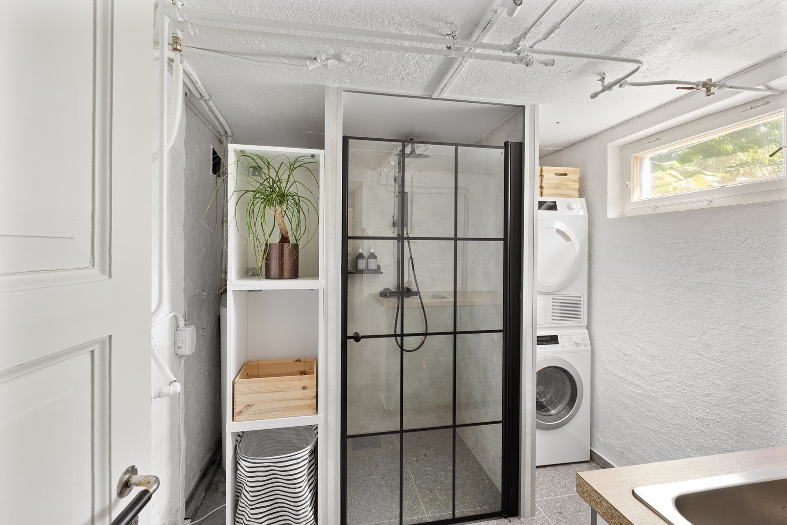 Praktisk vaskerom med opplegg for vaskemaskin og en dusjnisje med våtromsplater. Galleribilde