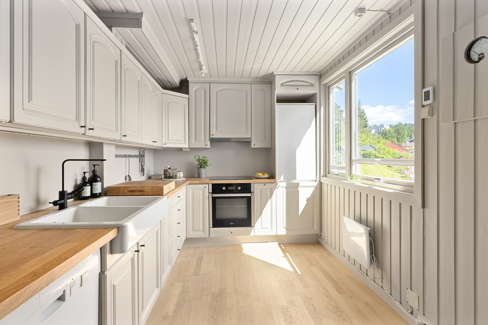 Elegant kjøkken med profilerte skap- og skuffefronter, benkeplate av eikelaminat og en stor dobbel oppvasskum i porselen. Galleribilde