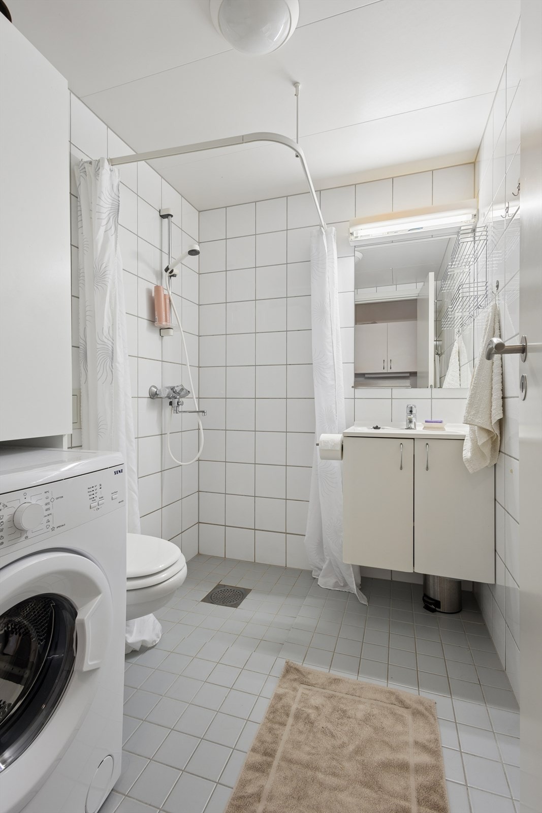 Badet er innredet med vegghengt toalett, servant med underskap og dusj. Galleribilde