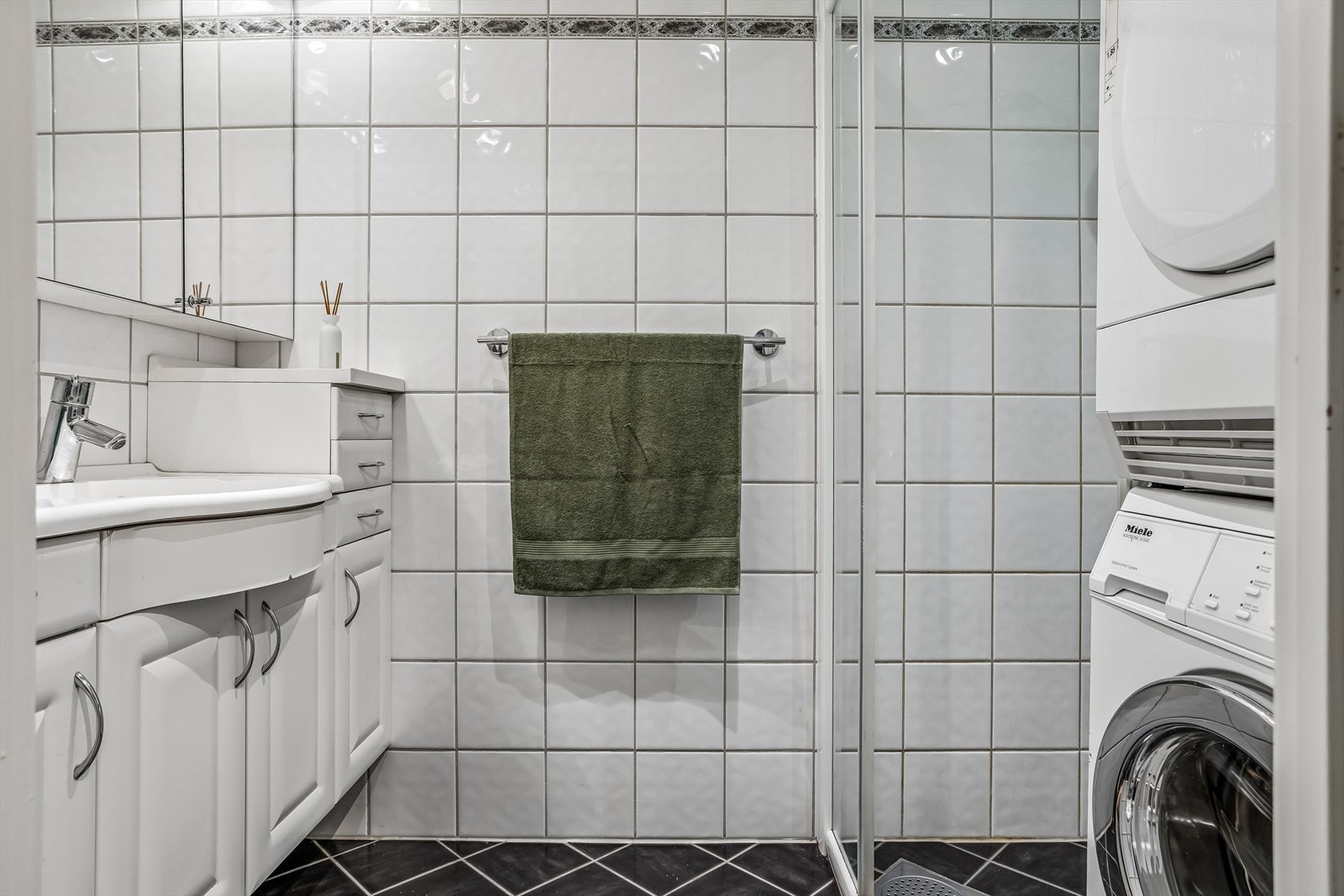 Flislagt bad med elektrisk gulvvarme, dusjhjørne med glassdører og opplegg for vaskemaskin og tørk. Galleribilde