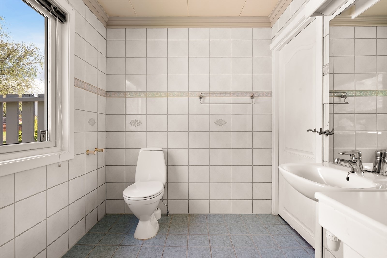 Badet er innredet med servant, speil med tilhørende belysning, dusjhjørne med glassdører og gulvmontert wc. Galleribilde