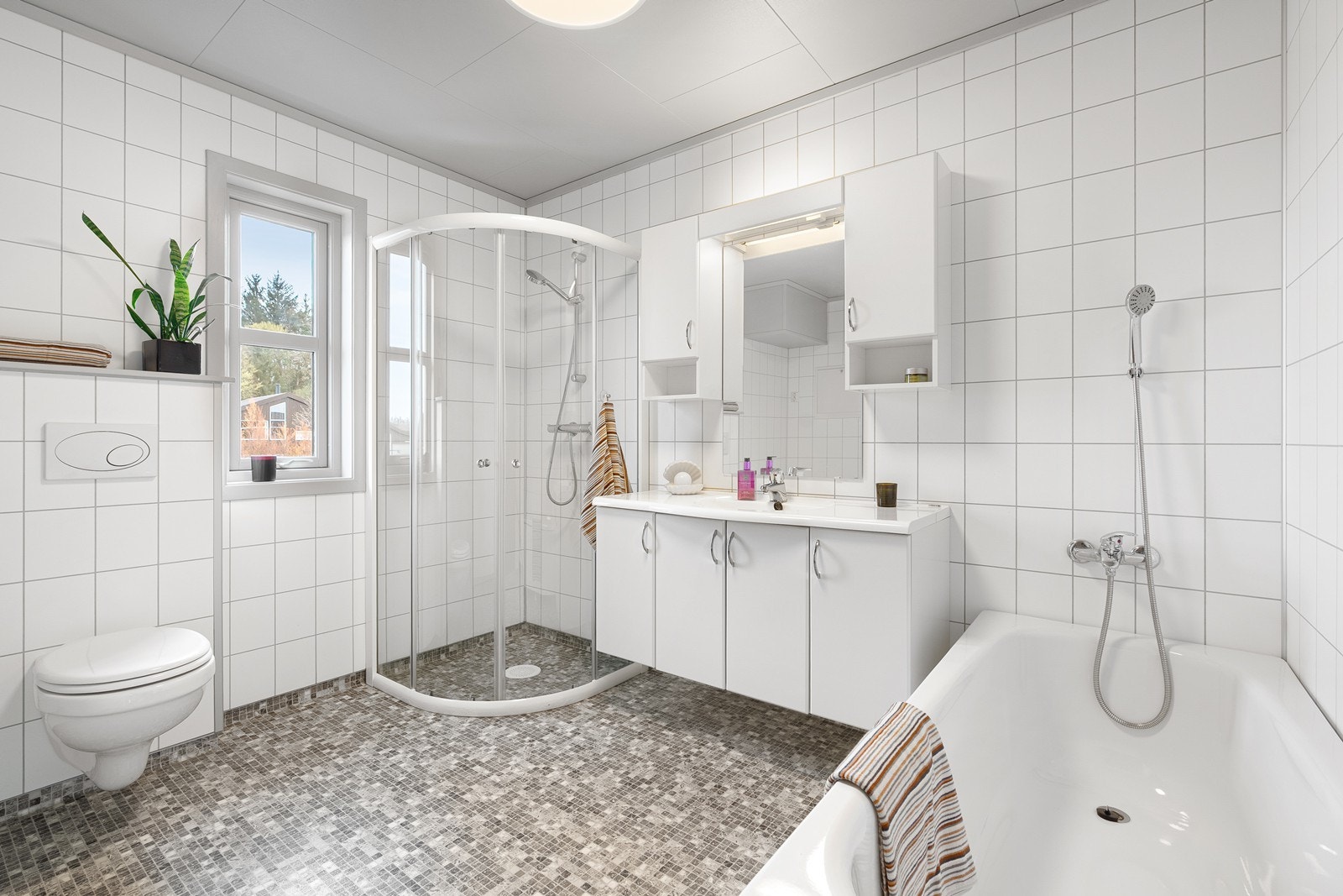 Pent baderom med vinylbelegg på gulv som gir en slitesterk og praktisk overflate. Veggene er kledd med baderomsplater, noe som gir et moderne og rent uttrykk. Galleribilde