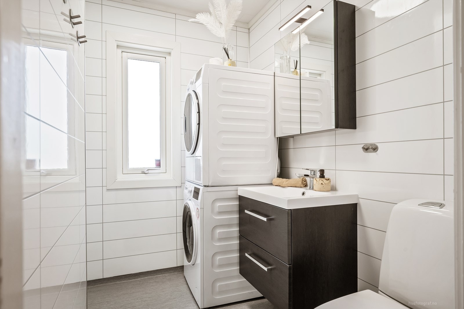 Badet i hovedetasjen har baderomsplater på veggene og opplegg for vaskemaskin. Galleribilde