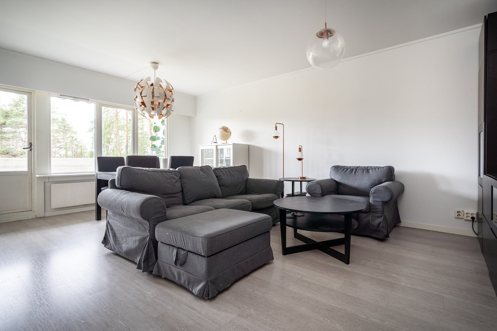 Dagslyset som strømmer inn via store vinduer gjenspeiles fint i de hvitmalte overflatene, og stuen har grått, tidsmessig laminat på gulvet. Galleribilde