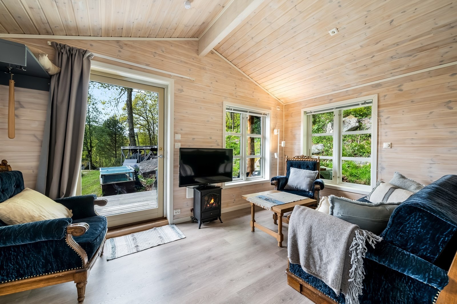 Stuen i annekset har utgang til terrasse og er innredet med beiset panel på vegger og i tak. Galleribilde