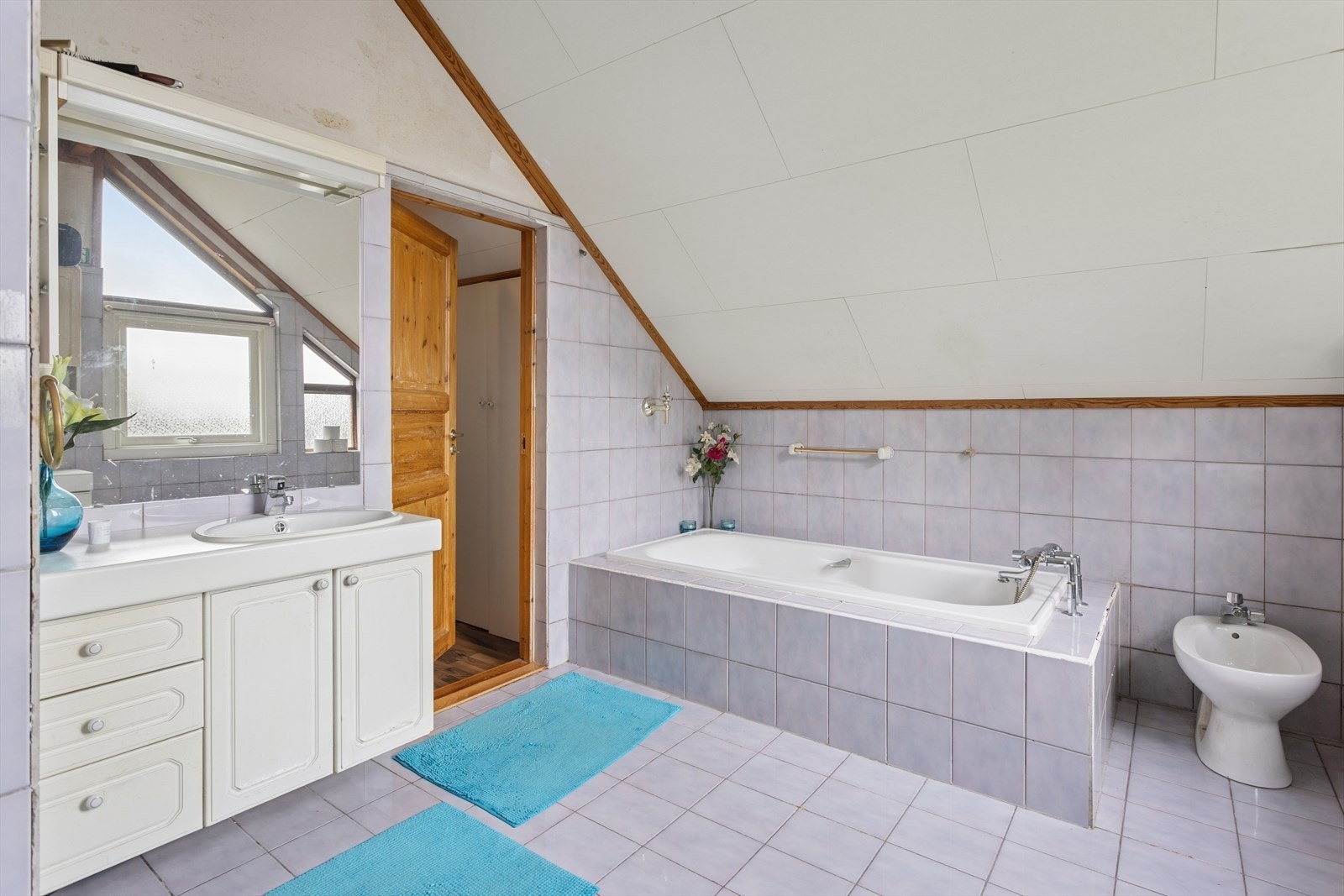 Videre er det speil på vegg med overliggende lysarmatur. Baderommet har også innmurt badekar, bidet og gulvstående toalett. Galleribilde