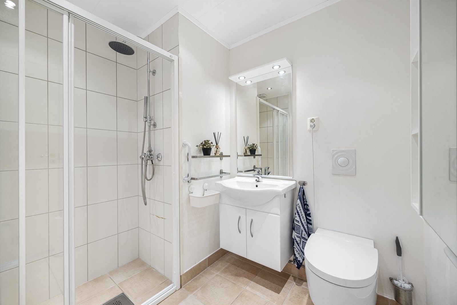 Badet er fliselagt på gulv og i dusj. Ellers våtromstapet på vegg. Badet har dusjnisje, lintøyskap, servantinnredning og vegghengt toalett, alt fra 2008. Galleribilde