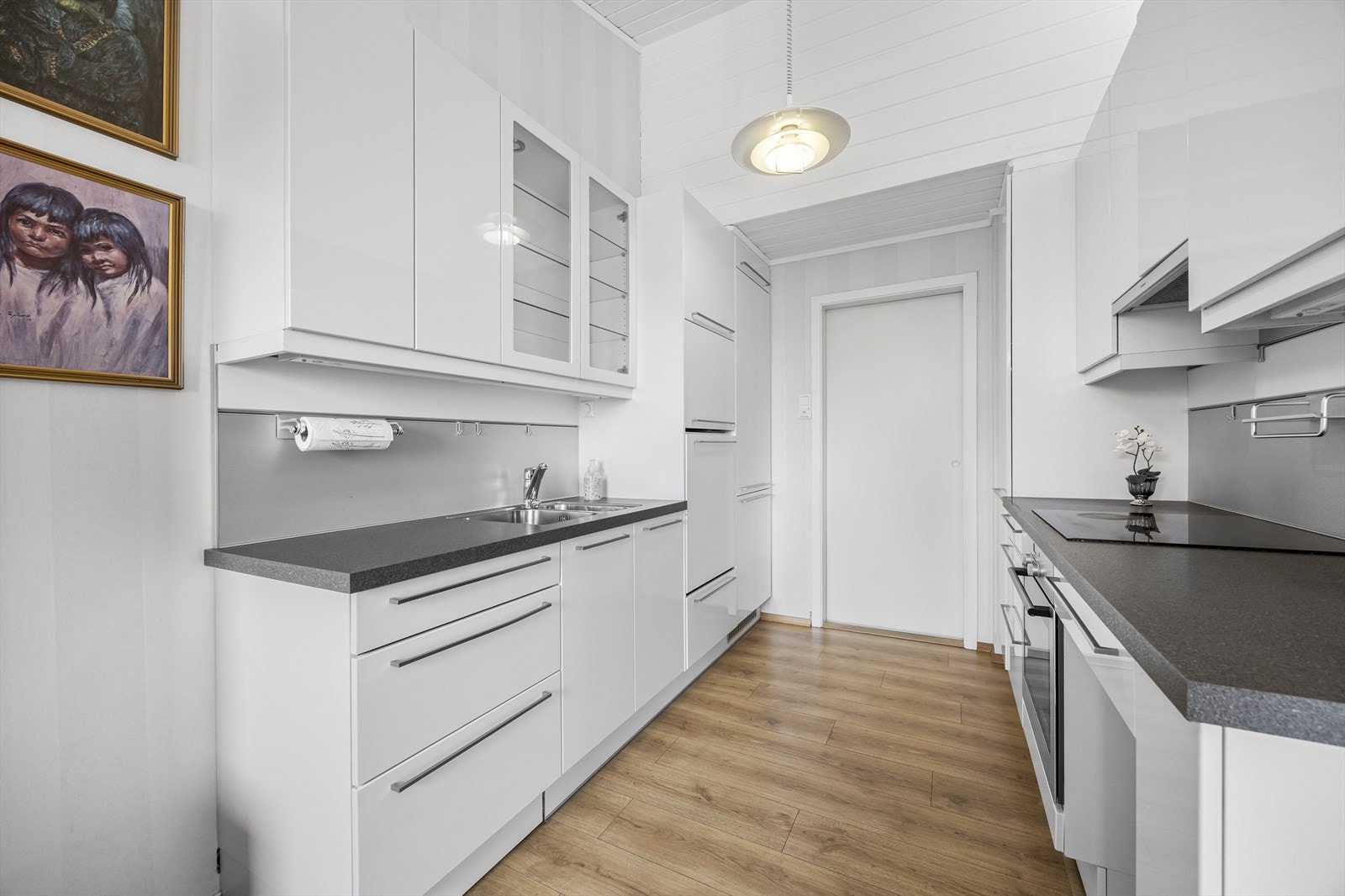 Kjøkkenet har innredning i hvit, høyglans fra HTH med plate over benk samt integrerte hvitevarer med komfyr, koketopp, oppvaskmaskin og kjøl- / fryseskap. Galleribilde