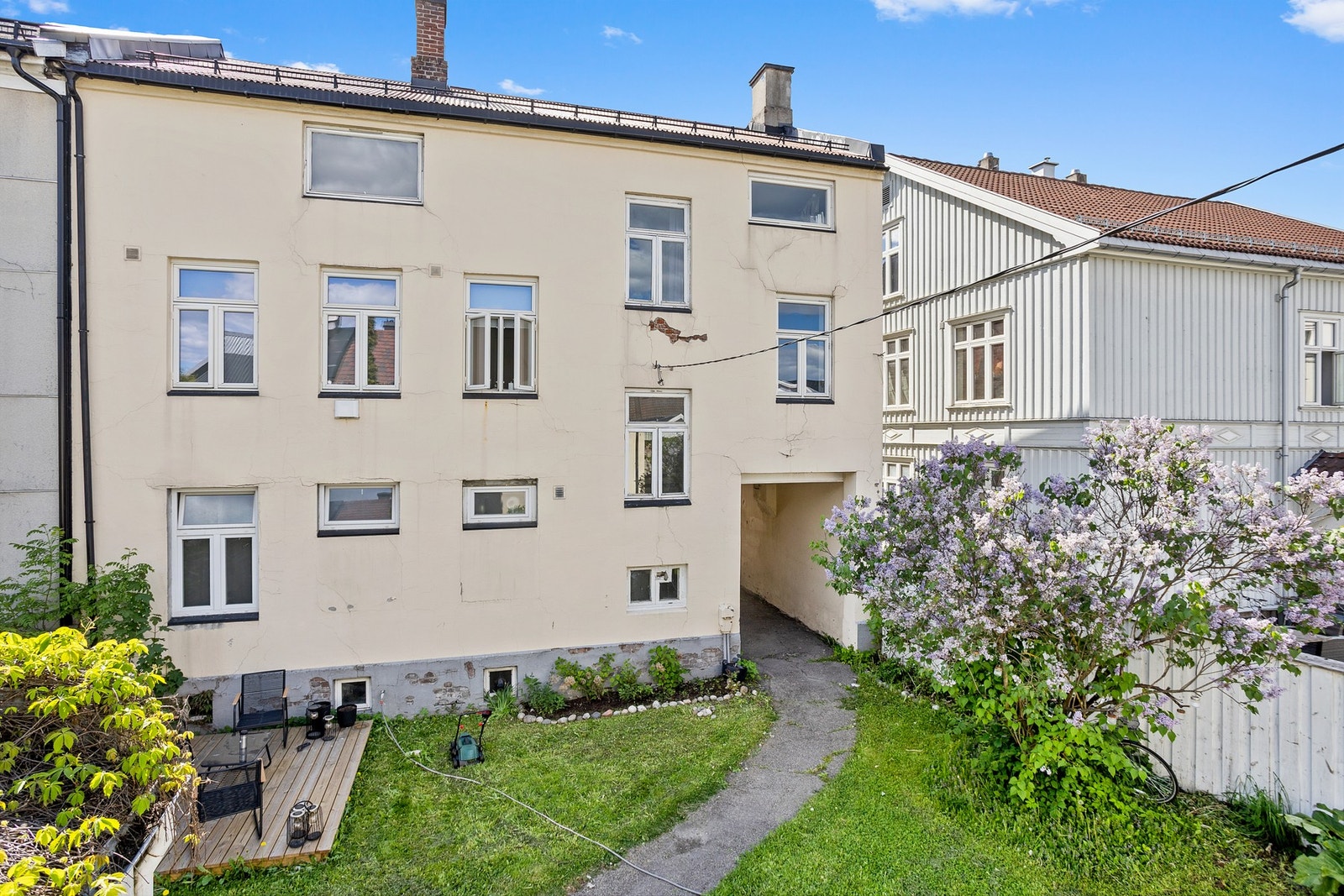 Skjermet og grønn bakgård med plen, blomstrende syriner og hyggelige uteområder som skaper en lun atmosfære rundt eiendommen Galleribilde