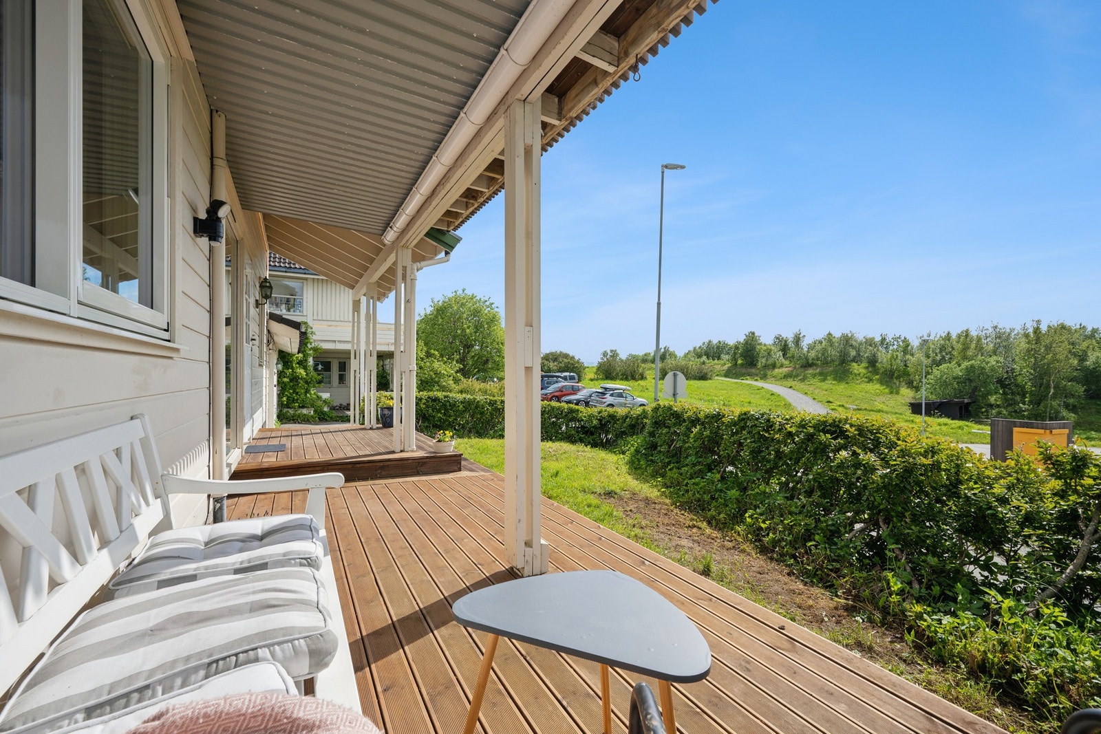 Overbygget inngangsparti med en hyggelig, trebelagt uteplass. Galleribilde