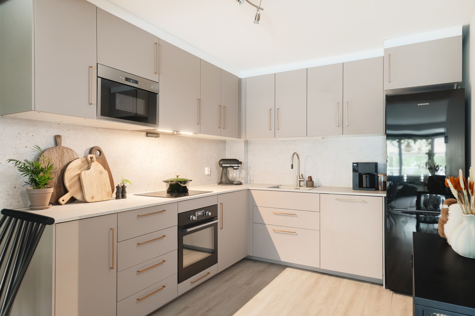 Lekkert kjøkken fra 2019 med rikelig med skap- og benkeplass i åpen løsning mot stuen. IKEA-innredningen har slette fronter som ble foliert i 2026, laminat benkeplate med nedfelt kum fra 2026 og backsplash mellom over- og underskap for enklere renhold. Galleribilde
