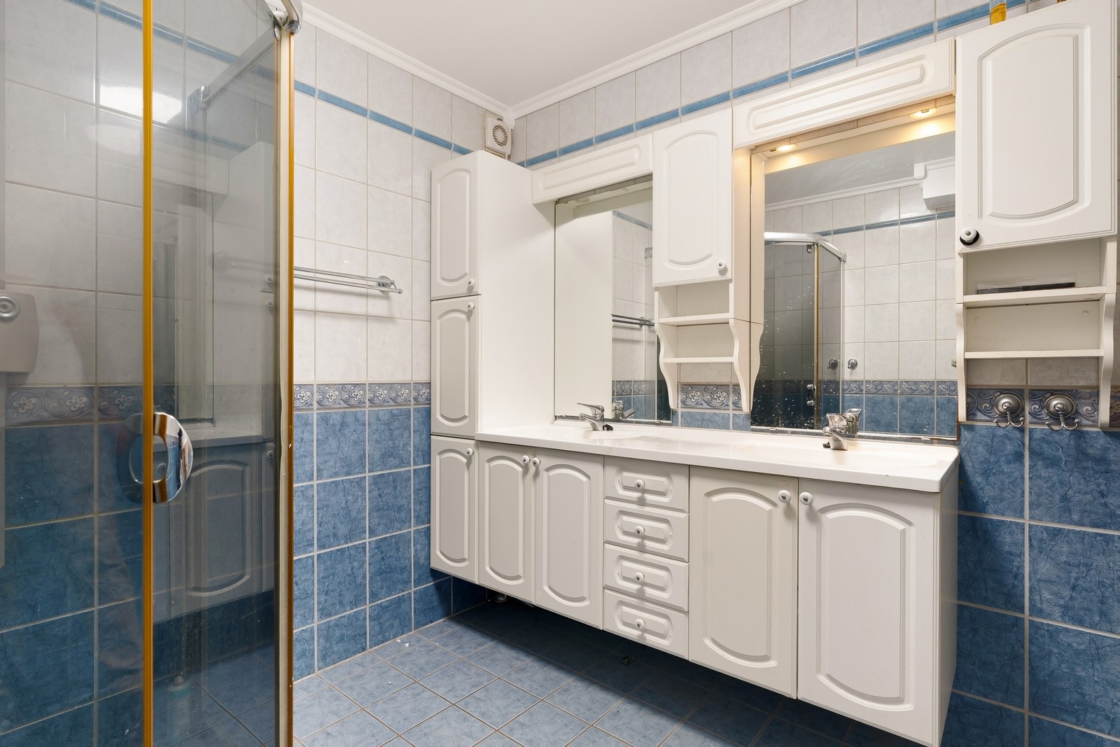 Badet er utstyrt med gulvstående WC, stor baderomsinnredning med dobbel servant og dusjhjørne Galleribilde
