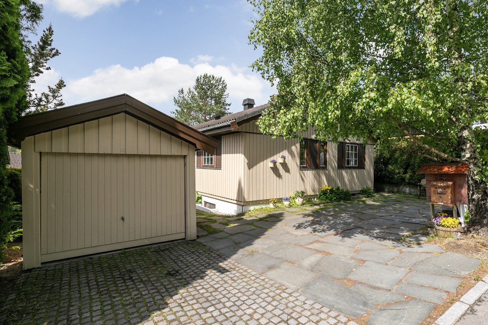 Garasjen er oppført i en trekonstruksjon med malt panel og takstein. Galleribilde