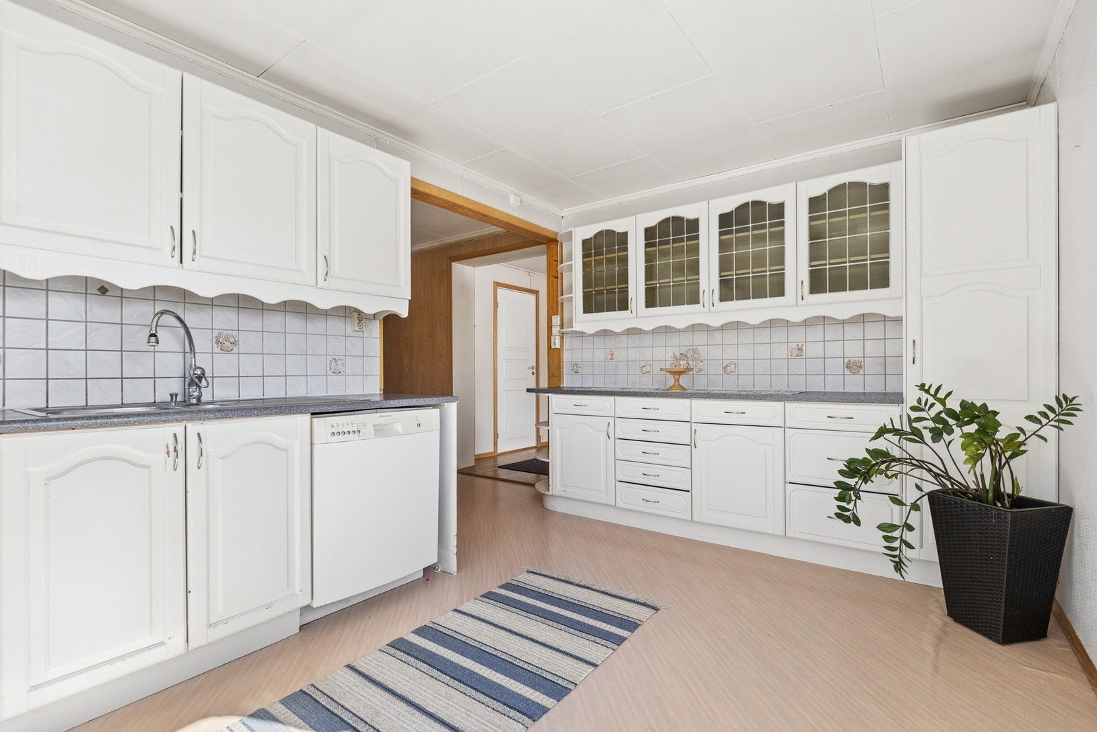 Kjøkkeninnredning med profilerte fronter, vitrineskap og rikelig med skap- og benkeplass. Galleribilde