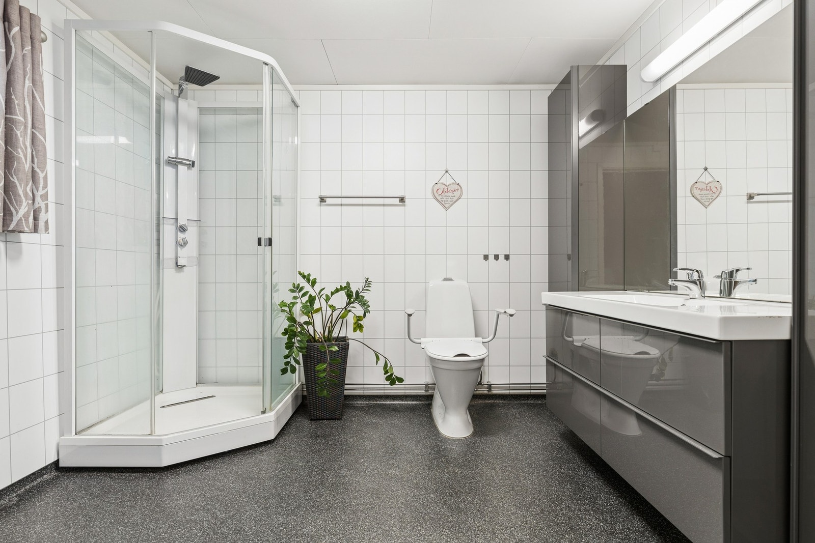 Romslig bad med flislagte vegger, dusjkabinett og moderne baderomsinnredning. Galleribilde