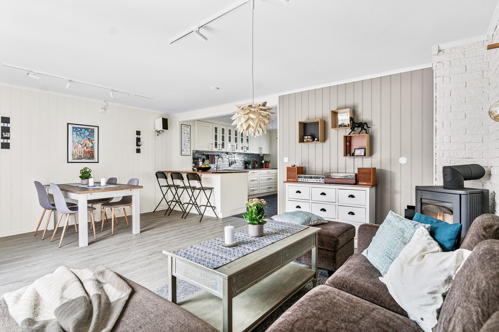 I hjørnet av rommet er det satt inn en peisovn som sørger for ekstra hygge i den kalde årstiden, og ved siden av terrassedøren er det montert en varmepumpe. Galleribilde