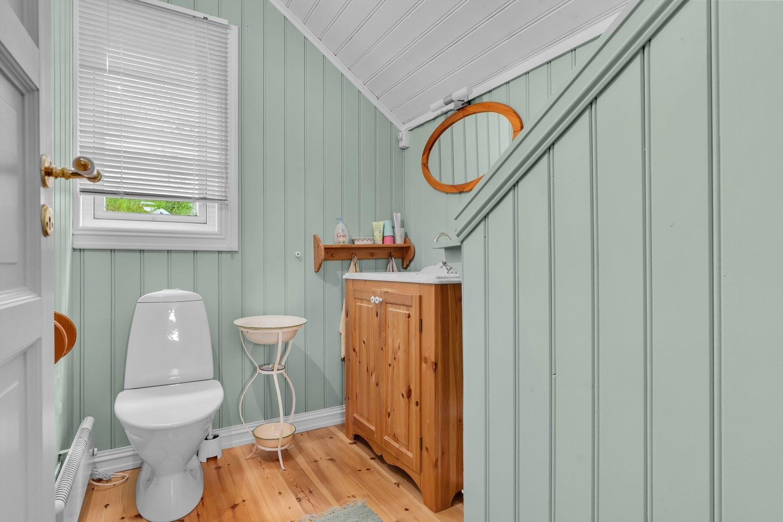 Praktisk toalettrom på loftet med panel på vegger og tak, og furugulv. Galleribilde